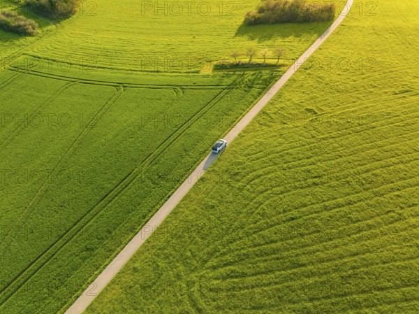 Sunlit landscape with car on lonely country road, ID3 VW, deer car sharing. Calw, Germany
