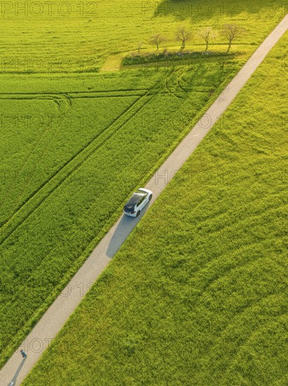 Narrow car drives on a country road through sunny green landscape, ID3 VW, deer car sharing. Calw, Germany