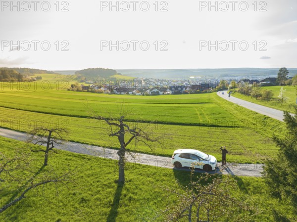 Car on the side of the road with a view of green fields and a village in the distance, ID3 VW, deer car sharing. Calw, Germany