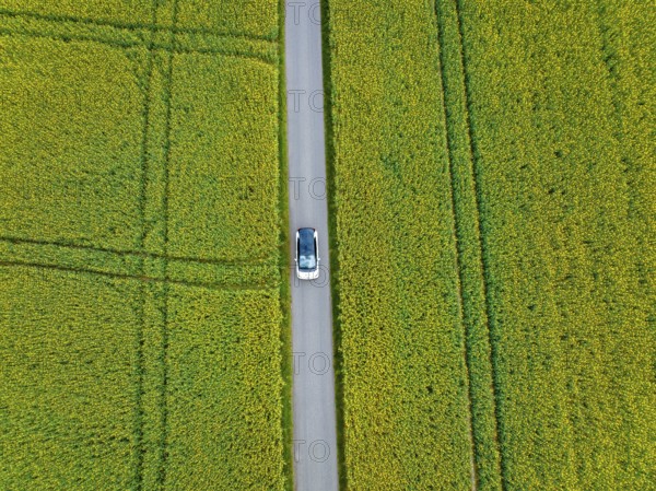 Aerial view of a car on a road between large fields, ID3 VW, deer car sharing. Calw, Germany