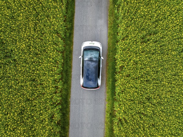 Aerial view of a car on a narrow road surrounded by green fields, ID3 VW, deer car sharing. Calw, Germany