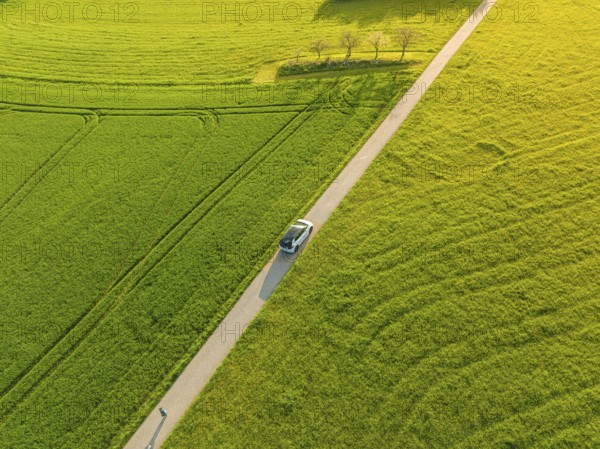 Car driving on a paved road through a sunny agricultural landscape, ID3 VW, deer car sharing. Calw, Germany