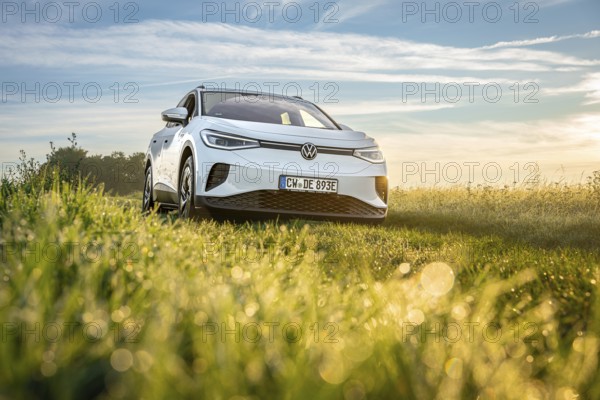 White car in a meadow at sunrise, peaceful natural environment, VW ID4 electric car, deer car sharing, Calw, Germany