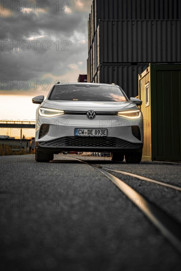 Silver car in front of dark containers at dusk, VW ID4 electric car, Deer Carsharing, Calw, Germany