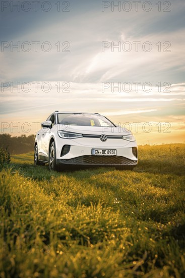 A white car is parked in a wide field in the light of the rising sun, VW ID4 electric car, Deer Carsharing, Calw, Germany