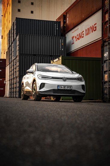 Silver car next to stacked containers at sunset, VW ID4 electric car, Deer Carsharing, Calw, Germany