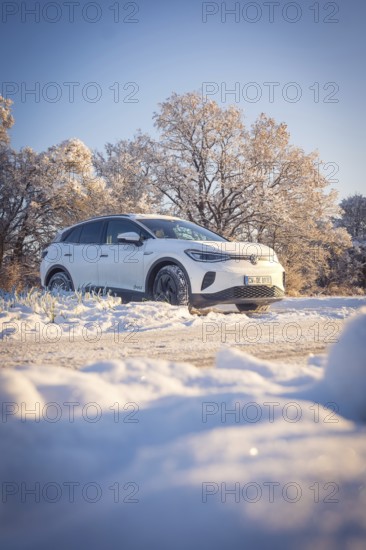 White car in snowy landscape with sunny sky and trees, VW ID4 electric car, Deer Carsharing, Calw, Germany