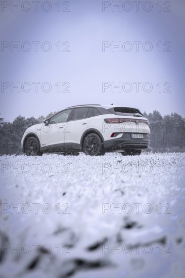 A car on snowy ground against a wooded background, VW ID4 electric car, Deer Carsharing, Calw, Germany
