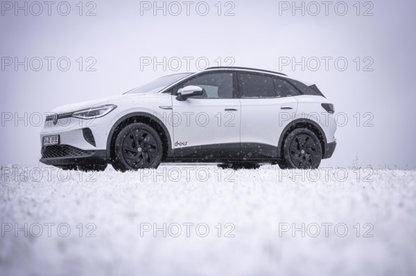 A car is standing in the snow surrounded by a wintry landscape, VW ID4 electric car, Deer Carsharing, Calw, Germany