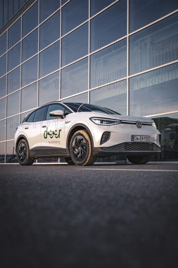 A car in front of a modern glass façade in an urban environment, VW ID4 electric car, Deer Carsharing, Calw, Germany