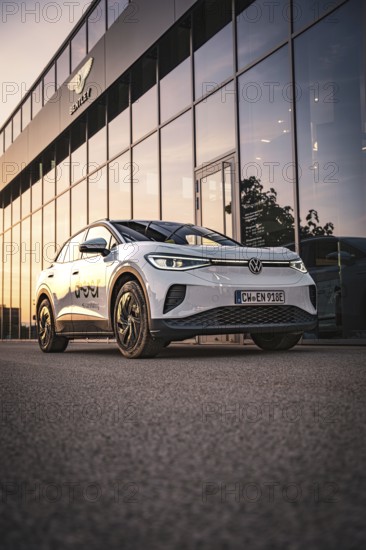 White car in front of a modern building at sunset, VW ID4 electric car, Deer Carsharing, Calw, Germany