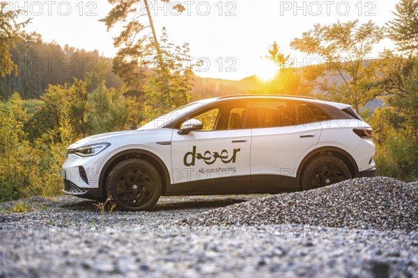 White car standing in gravel in front of sunset, VW ID4 electric car, Deer Carsharing, Calw, Germany