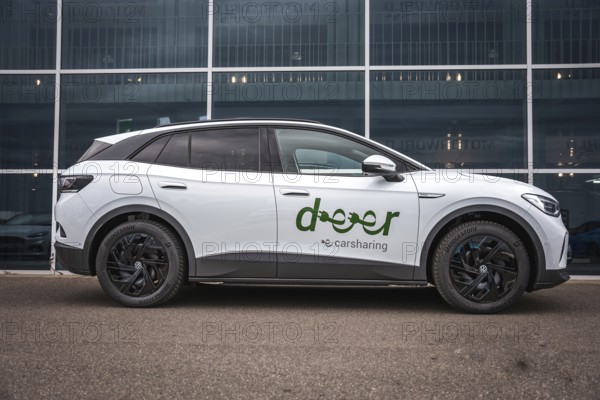 Side view of white car in front of modern offices, VW ID4 electric car, Deer Carsharing, Calw, Germany