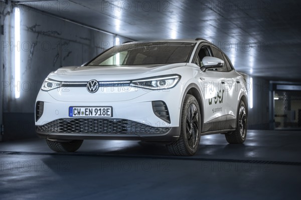 White Volkswagen in parking garage with LED lights and urban flair, VW ID4 electric car, Deer Carsharing, Calw, Germany