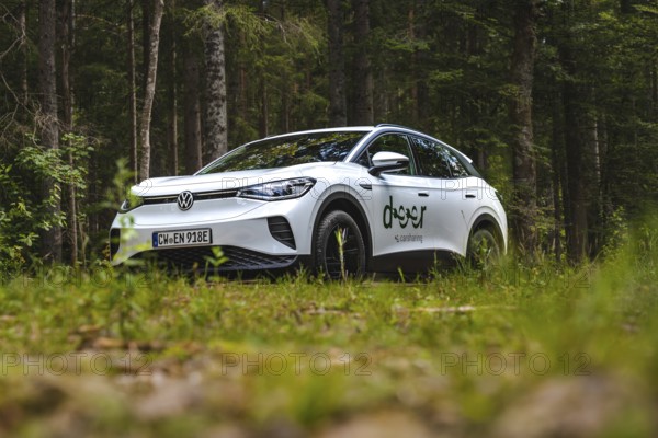 White Volkswagen in the forest, photographed from near the ground, VW ID4 electric car, Deer Carsharing, Calw, Germany