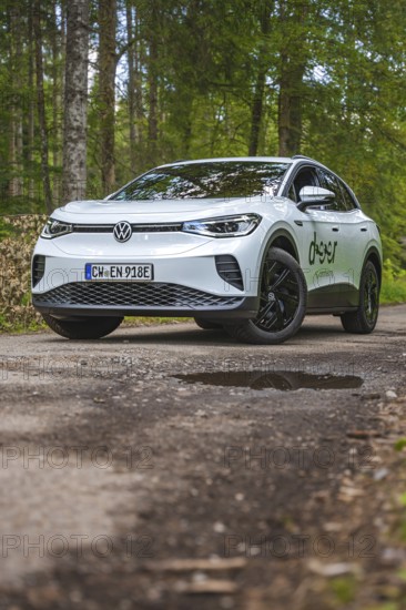 White car driving on a forest path surrounded by trees, VW ID4 electric car, Deer Carsharing, Calw, Germany