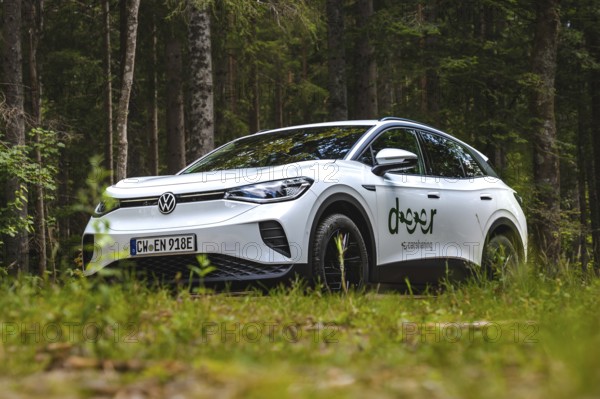 White Volkswagen in the forest from a low perspective, VW ID4 electric car, Deer Carsharing, Calw, Germany