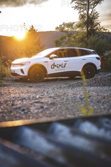 White Volkswagen in nature at sunset, VW ID4 electric car, Deer Carsharing, Calw, Germany