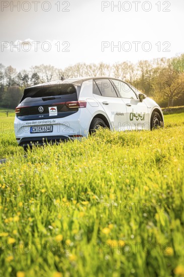White car on green field in sunshine surrounded by nature, VW ID4 electric car, Deer Carsharing, Calw, Germany