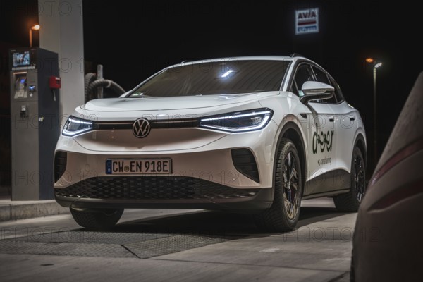 White Volkswagen at a gas station at night, VW ID4 electric car, Deer Carsharing, Calw, Germany