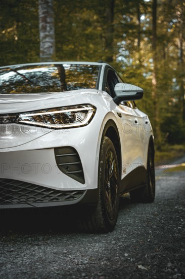White car in the forest, front view with clear tire display, VW ID4 electric car, Deer Carsharing, Calw, Germany