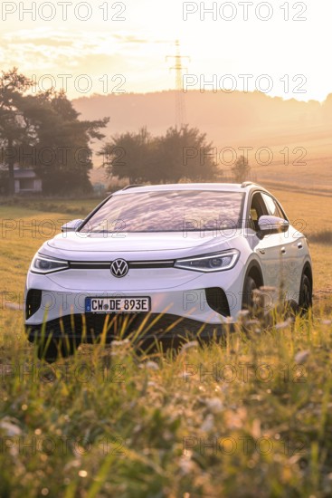 White car in a field at sunrise surrounded by gentle landscape, VW ID4 electric car, deer car sharing, Calw, Germany