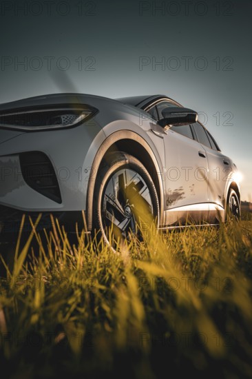 Low perspective shot of a car in a meadow at sunset, VW ID4 electric car, Deer Carsharing, Calw, Germany