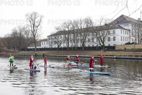 Water sports enthusiasts dressed up as Santa Claus ride SUPs on the Spree in front of Bellevue Palace in Berlin on 30.11.2025