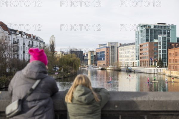 Passers-by watch water sports enthusiasts disguised as Santa Claus with SUPs on the Spree on the Spree in Berlin on 30.11.2025