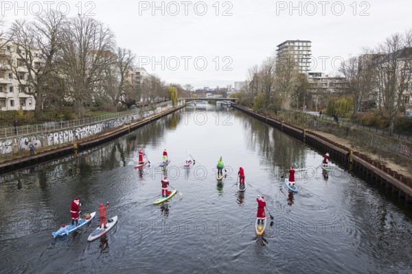 Water sports enthusiasts dressed up as Santa Claus ride SUPs on the Spree on the banks of the Hansa in Berlin on 30.11.2025