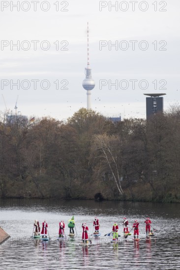 Water sports enthusiasts dressed up as Santa Claus ride SUPs on the Spree am Park at the presidential triangle in Berlin on 30.11.2025