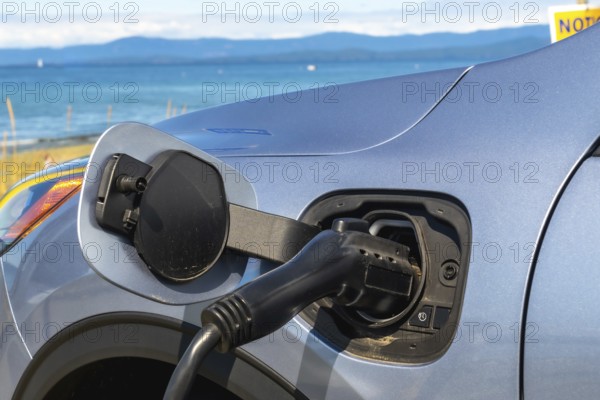 Electric car is being charged at a station by the sea, promoting eco friendly travel and highlighting the growing adoption of sustainable transportation solutions