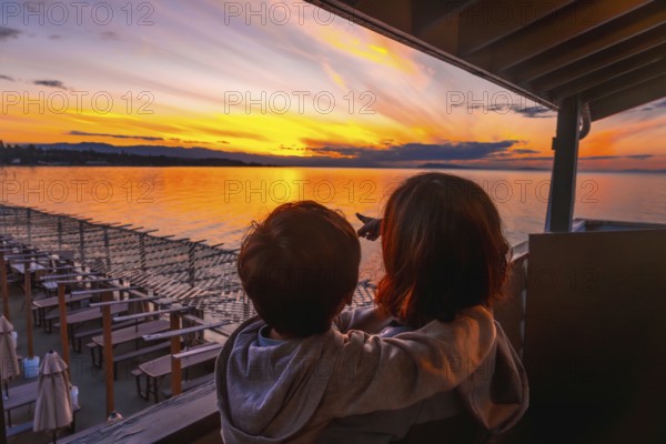 Mother and son bonding while enjoying breathtaking golden sunset view over qualicum beach on vancouver island, creating cherished family memories during summer vacation