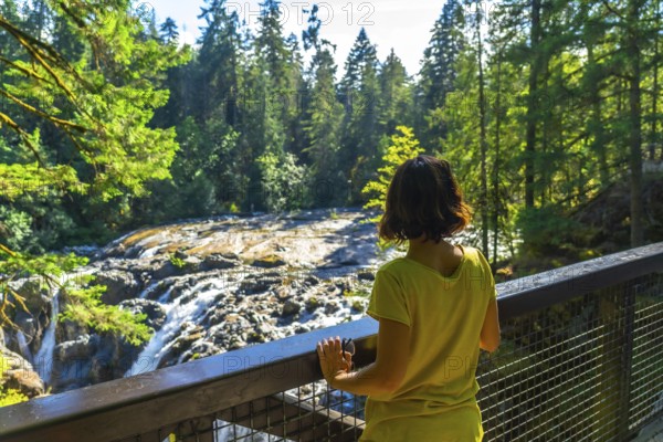 Female tourist admiring englishman river falls in vancouver island, british columbia, canada, enjoying the beautiful nature during summer holidays