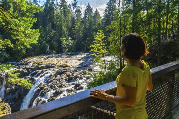 Tourist wearing a yellow t shirt is enjoying the view of englishman river falls from a viewpoint on vancouver island, british columbia, canada, during a sunny summer day