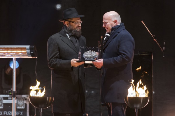 Kai Wegner (Governing Mayor of Berlin) receives a gift from Yehuda Teichtal (Rabbi of the Chabad-Lubavitch movement) at the lighting of the 20th anniversary of Hanukkah in front of the Brandenburg Tor, Berlin, 17 December 2025