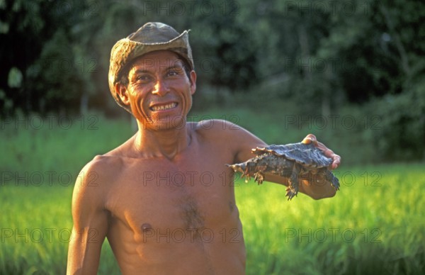 A man who runs a small private zoo near Iquitos on the Amazon shows a turtle, Peru, South America, September 1997, vintage, retro, old, historic