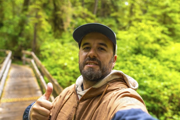Tourist taking a selfie on a wooden boardwalk path, surrounded by lush rainforest vegetation, enjoying the scenic beauty of ucluelet on vancouver island, canada