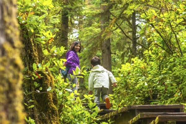 Mother and son enjoying a hike through a lush rainforest trail in ucluelet, located on vancouver island, british columbia, canada, surrounded by vibrant green foliage and moss covered trees
