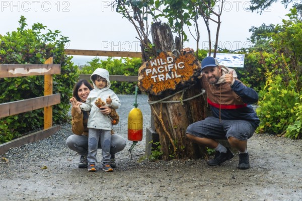 Happy family posing for a photo at the entrance of the wild pacific trail in ucluelet, british columbia, canada, enjoying a day outdoors surrounded by nature