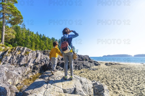 Mother and son holding hands. Exploring the beautiful rocky coastline near a sandy beach in tofino. Vancouver island. British columbia. Canada. Enjoying the stunning ocean view on a sunny summer day