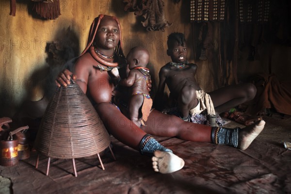 Himba woman sitting with baby, Himba perfume, scented smoke from burning plants, Himba village, Kaokoveld, Kunene, Namibia