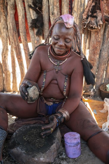 Himba woman grinding grain on a stone, Himba village, Kaokoveld, Kunene, Namibia