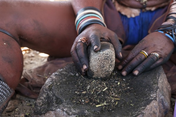 Himba woman grinding grain on a stone, Himba village, Kaokoveld, Kunene, Namibia