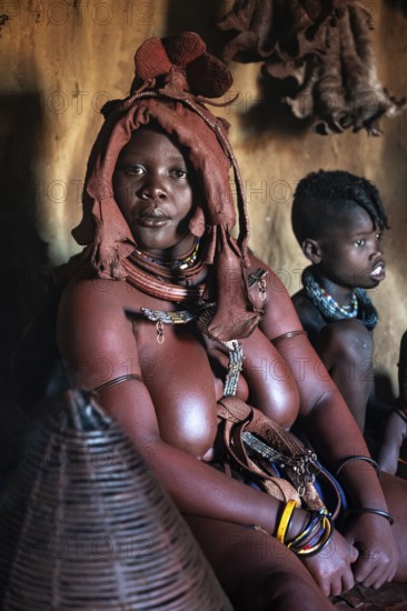 Himba woman sitting with baby, Himba perfume, scented smoke from burning plants, Himba village, Kaokoveld, Kunene, Namibia