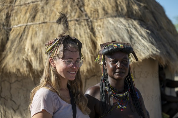 Tourist and local in the village, Hakaona tribe, also Havakona or Hakawona, near Opuwo, Kunene, Namibia