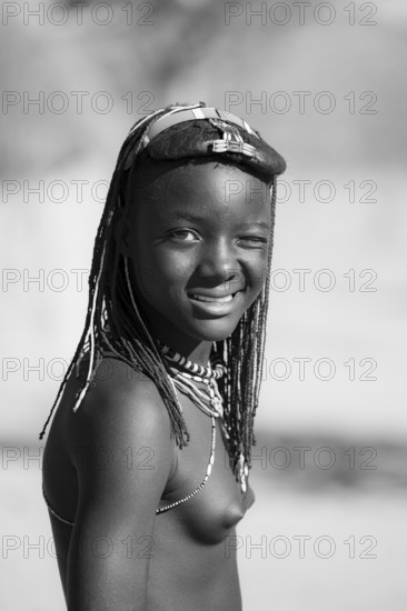 Black and white, portrait, brightly decorated girl winking, Hakaona tribe, also Havakona or Hakawona, near Opuwo, Kunene, Namibia