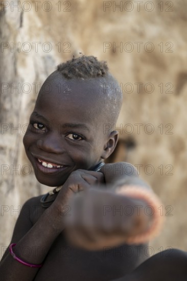 Happy Himba child punching funny at the camera, traditional Himba village, Kaokoveld, Kunene, Namibia