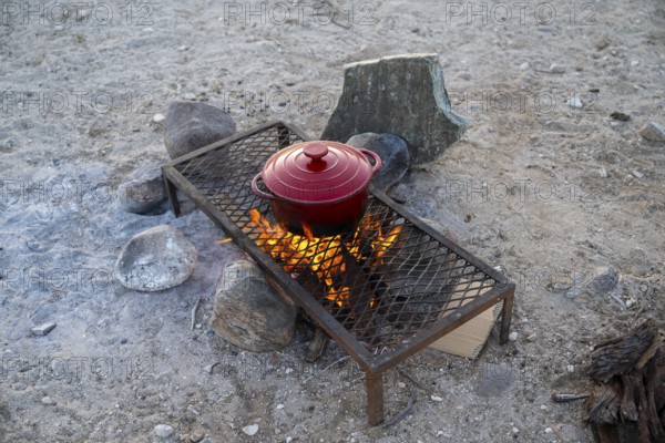 Single pot cooks on a campfire, preparing food while camping