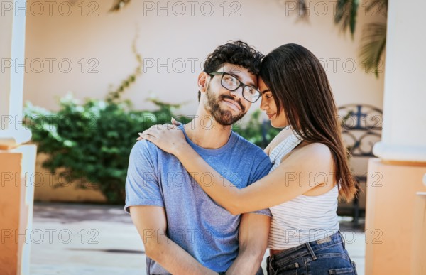 Attractive girl tenderly hugging her boyfriend outdoors. Girl hugging her boyfriend while he smiles at her, Happy couple, Girl hugging her boyfriend outside